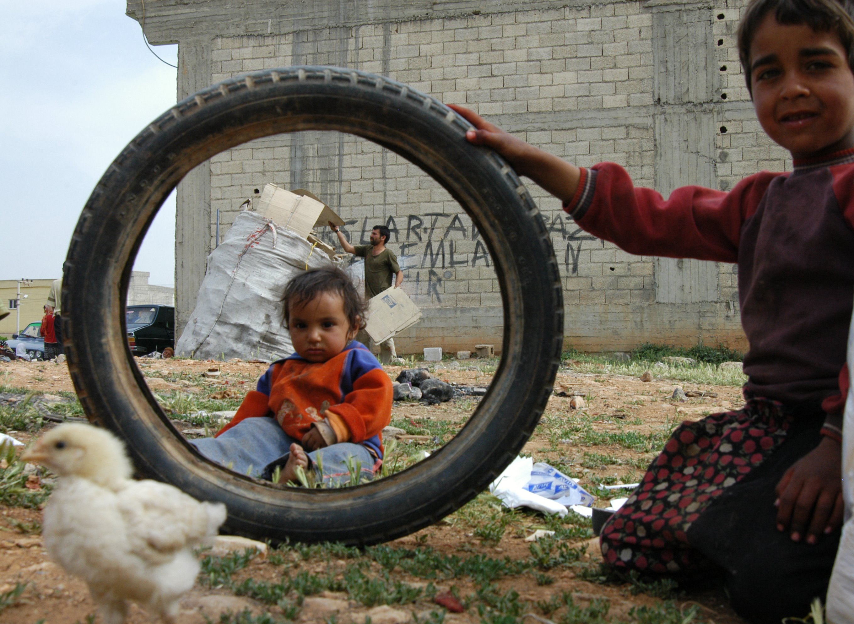 Two Dom children play as adults collect waste paper. Photo: Kemal Vural Tarlan